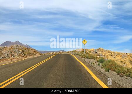 Segnale stradale curvy sulla strada deserta vuota del deserto di Atacama, Cile del Nord, Sud America Foto Stock