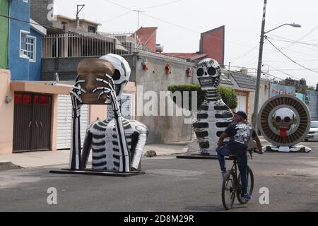 Città del Messico, Messico. 30 Ott 2020. CITTÀ DEL MESSICO, MESSICO - OTTOBRE 30: Una persona indossa la maschera mentre cammina davanti a un monumentale cranio fatto di cartone, sono stati messi per decorare le strade di Tlahuac per celebrare il giorno dei morti ( dia de Muertos) in mezzo a Covid-19 pandemia. Il 30 ottobre 2020 a Città del Messico, Messico. Credit: Ismael Rosas/Eyepix Group/The Photo Access Credit: The Photo Access/Alamy Live News Foto Stock