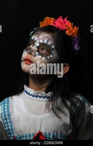 Città del Messico, Messico. 30 Ott 2020. CITTÀ DEL MESSICO, MESSICO - OTTOBRE 30: Una ragazza guarda la macchina fotografica, mentre posa con il suo volto make-up come cranio, per celebrare il giorno messicano dei morti, la tradizione dei bambini che chiedono dolci da porta a porta, È stato sospeso come precauzione per evitare nuovi casi a causa del Covid-19 il 30 ottobre 2020 a Città del Messico, Messico. Credit: Ricardo Castelan Cruz/Eyepix Group/The Photo Access Credit: The Photo Access/Alamy Live News Foto Stock