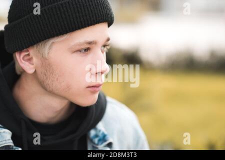 Elegante ragazzo di 15-16 anni che indossa cappello nero lavorato a maglia e felpa con cappuccio all'aperto da vicino. Stagione autunnale. Teenagerhood. Foto Stock