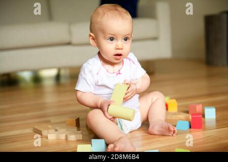 Un bambino divertente strisciante all'interno a casa giocare con blocco Foto Stock