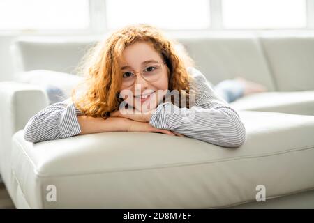 Ragazza adolescente rossa positiva sdraiata su un divano. Foto Stock