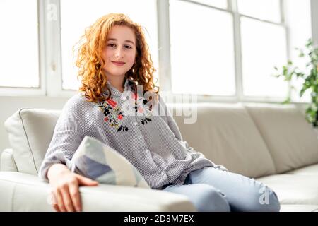 Ragazza adolescente rossa positiva sdraiata su un divano. Foto Stock