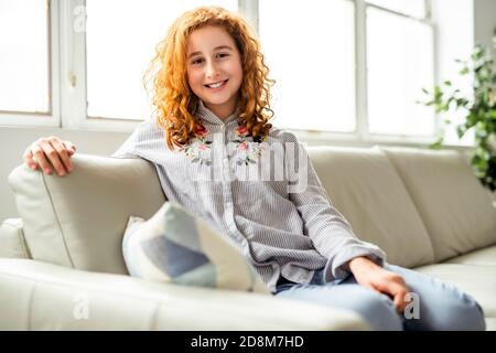 Ragazza adolescente rossa positiva sdraiata su un divano. Foto Stock