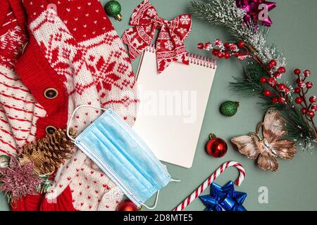 Mockup creativo fatto di giocattoli di Natale, rami di albero e maglioni con blocco note vuoto. Tema di Natale e Capodanno. Foto Stock