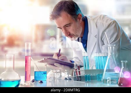 Tecnico chimico di laboratorio che scrive i risultati in una cartella in un laboratorio. Composizione orizzontale. Vista frontale. Foto Stock