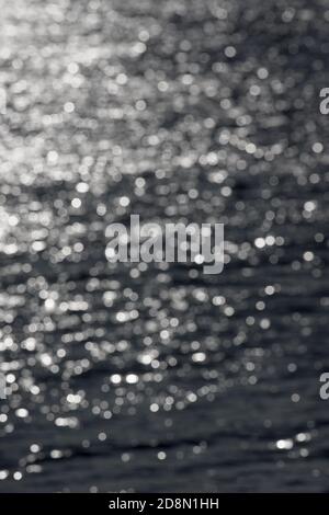 5 - immagine verticale sfocata di ondate di acqua soleggiate, formando uno sfondo astratto e testurizzato chiaro di cerchi bokeh bianchi casuali. Tema dell'acqua. Foto Stock