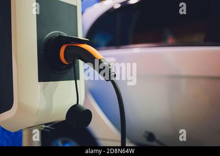 Immagine a colori di una mano di un uomo la preparazione per caricare un auto elettrica. Foto Stock