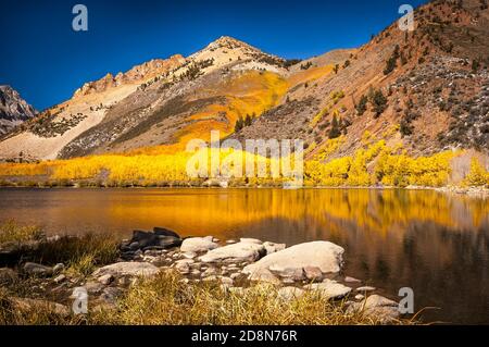 I colori autunnali su una montagna si riflettono su un lago tranquillo nella valle di Owens. Foto Stock