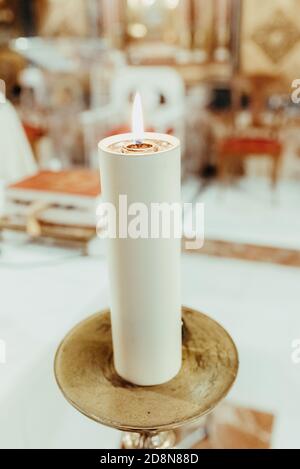 Una grande candela religiosa illuminata all'interno di una chiesa. Foto Stock