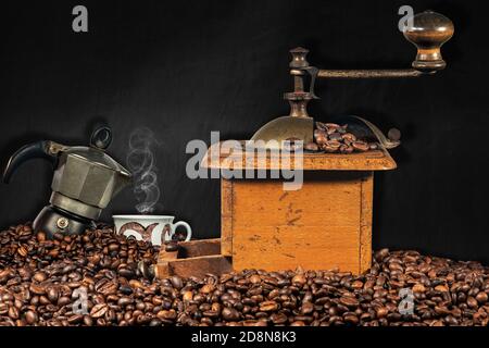 Vecchio macinacaffè manuale, macchina per caffè italiana e una tazza su un mucchio di chicchi di caffè tostati con lavagna vuota sullo sfondo. Foto Stock