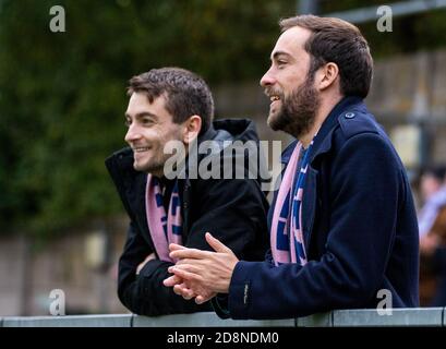 Due amici e tifosi guardano una partita di calcio femminile del Dulwich Hamlet FC, con sciarpe rosa e blu. Foto Stock