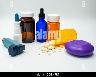 Vari flaconi di farmaco, inalatore, spray nasale, e gocce su uno sfondo bianco. Foto Stock