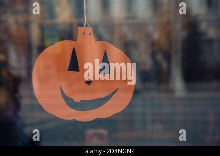 Arancione brillante Halloween spaventoso carta di emozioni faccia nella finestra di caffè, fuoco selettivo. Foto Stock