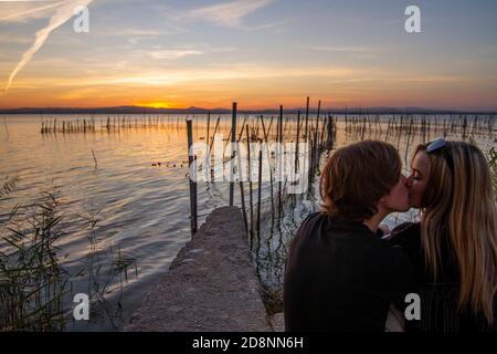 Concetto di amore. Coppie di nozze non identificate guardare il tramonto seduto accanto al lago 'la Albufera' a Valencia, Spagna Foto Stock