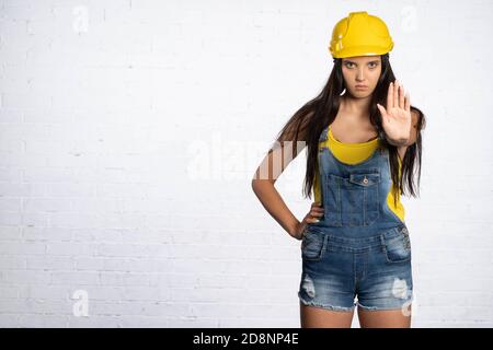 Una lavoratrice di costruzione femminile arresta il traffico su un cantiere. Giovane signora ingegnere. La donna mostra di fermarsi. Foto Stock