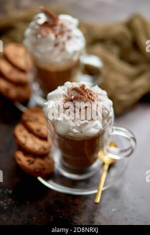 Due bicchieri alti con cioccolata calda, panna montata e polvere di cannella sopra Foto Stock