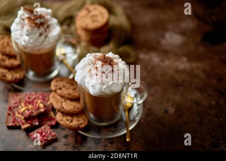 Due bicchieri alti con cioccolata calda, panna montata e polvere di cannella sopra Foto Stock