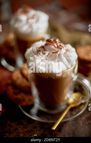 Due bicchieri alti con cioccolata calda, panna montata e polvere di cannella sopra Foto Stock