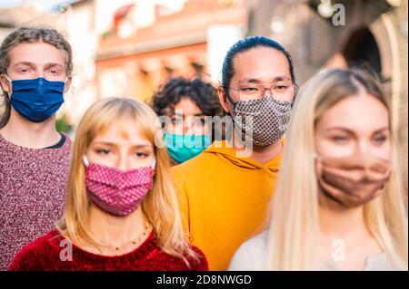 Gruppo di amici multirrazziali che camminano per le strade della città - nuovo normale concetto di viaggio con i giovani coperti da maschera protettiva - Focus su AS Foto Stock