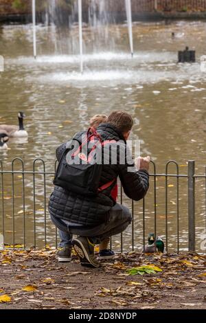 un padre che mostra il suo figlio giovane anatre e cigno dentro un parco che insegna al figlio di nutrire gli uccelli Foto Stock