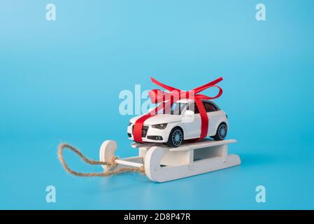Foto in primo piano di dimensioni complete di stile moderno e piacevole mini auto di colore bianco con prua sul tetto in piedi slitte in legno isolate su una parte posteriore blu brillante Foto Stock