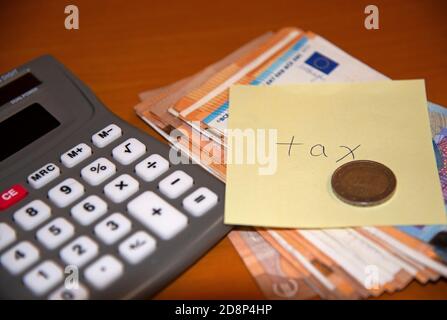 Imposta sul reddito scritta su nota post-it con banconote, moneta e calcolatrice. Concetto: Pagamento dell'imposta sul reddito. Foto Stock