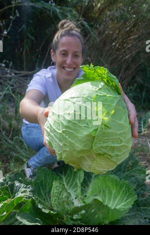 Donna felice con un cavolo in mani smiling.Harvest in orto, sano stile di vita alimentare. Foto Stock