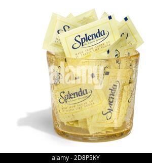 Un contenitore di vetro giallo pieno di pacchetti Splenda fotografati sopra uno sfondo bianco Foto Stock