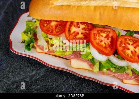 Composto da pane francese, formaggio muenster, salame e verdure. Prendete il concetto di cibo o fast food. Foto Stock