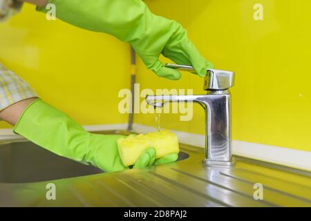 Primo piano della cucina di pulizia, mani della donna in guanti di gomma con spugna Foto Stock