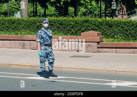 Giovane soldato della Guardia Russa che indossa camuffamento estivo, maschera protettiva e guanti che lavorano per la strada Foto Stock