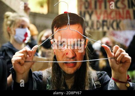 Cracovia, Polonia. 28 Ott 2020. Un protestore che indossa una maschera con un volto del ministro della giustizia polacco e avvocato generale, Zbigniew Ziobro detiene una gruccia, come simbolo di aborti illegali durante la manifestazione. La Corte costituzionale polacca nella sua nuova, il tribunale scelto politicamente ha stabilito che l'aborto è incostituzionale nei casi in cui vi è un'alta probabilità di danni gravi e irreversibili al feto o di una malattia incurabile che minaccia la sua vita. Nel caso della Polonia, ciò significa un divieto quasi totale dell'aborto. A seguito della decisione del tribunale, sono iniziate in sempre grandi proteste Foto Stock