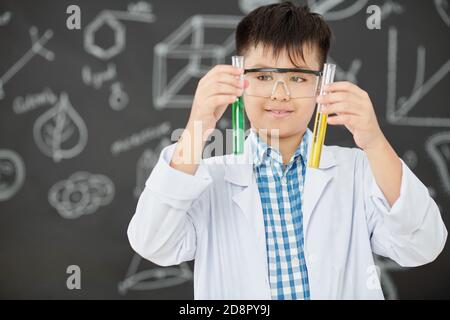 Studente di scuola che guarda le provette Foto Stock