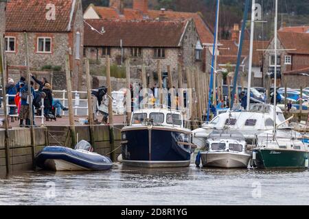 barche lungo il muro a blakeney sulla costa nord del norfolk con turisti che si sbadano con le linee lungo la banchina. Foto Stock