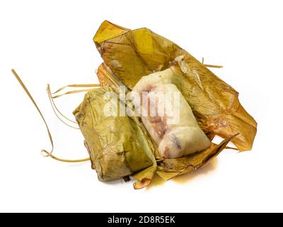 Il primo piano di riso thai al vapore appiccicoso con latte di cocco e banana (Khao Tom Mud) avvolto da foglie di banana su sfondo bianco. Foto Stock