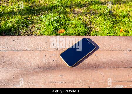 Telefono cellulare perso sul banco nel parco Foto Stock