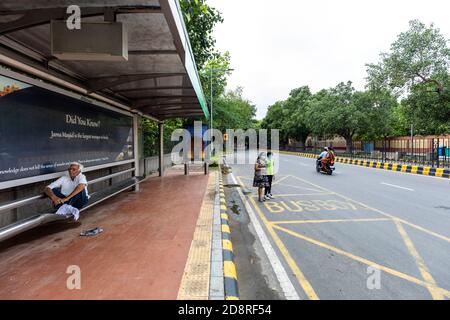 Le persone che si trovano in una stazione degli autobus locali a Nuova Delhi in attesa dei trasporti pubblici. Foto Stock