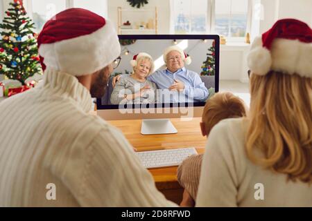 La giovane famiglia che soggiorna a casa durante le vacanze di Natale, ma di mantenere in contatto con i nonni Foto Stock