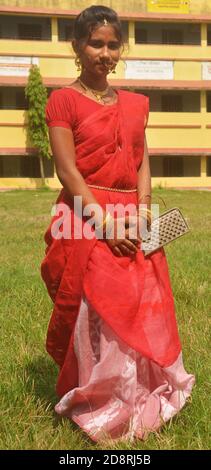 Primo piano di una ragazza indiana bengalese adolescente con lunghi capelli scuri che indossano tradizionali sari rossi con borsa a braccetti e anello per il naso di gioielleria, orecchini. Foto Stock