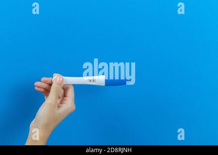 test di gravidanza positivo su sfondo blu nelle mani di una ragazza Foto Stock