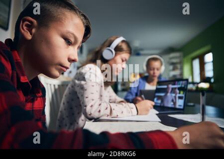 Lezione di scuola online. I bambini imparano via Internet con i laptop a casa. Foto Stock