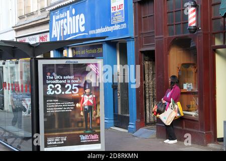 Ayr, Ayrshire, Scozia, Regno Unito. Fotografia di strada candida intorno ad Ayr. Wona con le borse per lo shopping che si sono stancate mentre aspetta dalla fermata dell'autobus Foto Stock