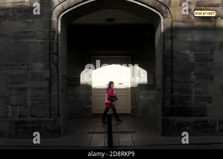 Ayr, Ayrshire, Scozia, Regno Unito. Fotografia di strada candida intorno ad Ayr. Donna in giacca luminosa a strisce in arco Foto Stock