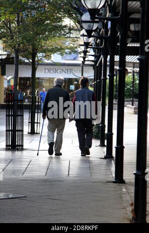 Ayr, Ayrshire, Scozia, Regno Unito. Fotografia di strada candida intorno ad Ayr. La coppia anziana tiene le mani nel centro commerciale Foto Stock