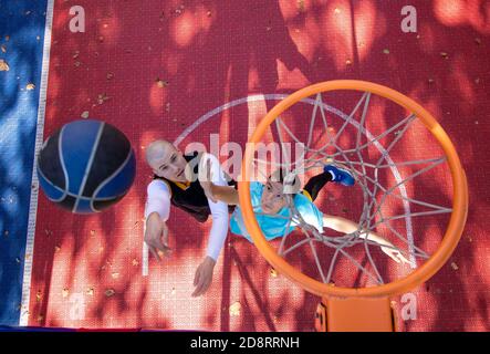 Fratelli che giocano a basket uno su uno. Sparare al cesto e guardare il volo della palla. Vista dall'alto sulla rete. Concetto di stile di vita sano. Foto Stock