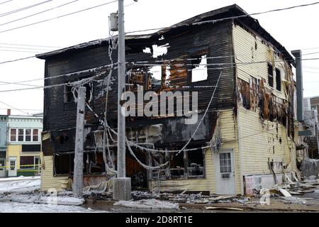 Un edificio bruciato in un angolo di strada in inverno. L'edificio è completamente bruciato e sembra colapse. Foto Stock