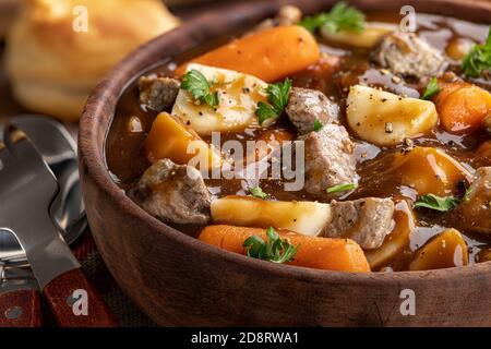 Primo piano di una ciotola di legno di stufato di manzo con carote e patate Foto Stock