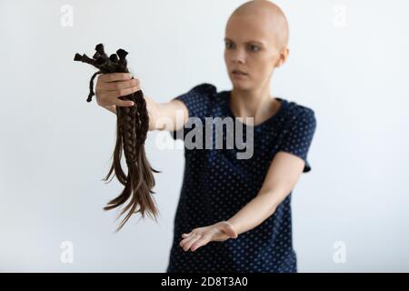Primo piano infelice temuta donna giovane senza capelli che tiene i capelli Foto Stock