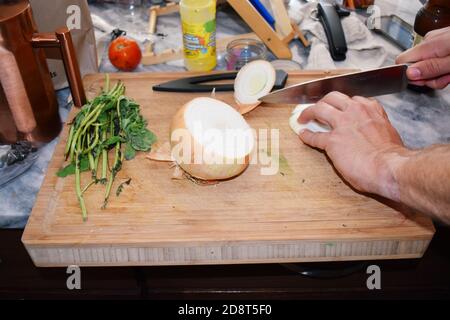 Preparazioni alimentari, tagliere in legno con coltello alle erbe fresche sull'isola della cucina. Foto Stock